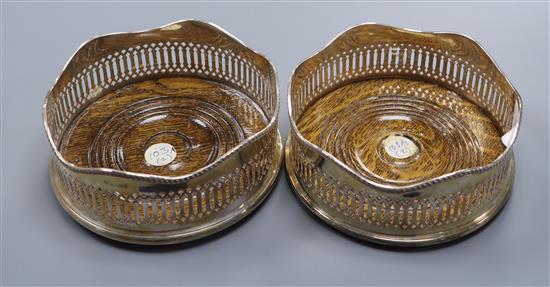 A pair of modern pierced silver George III style wine coasters, with oak bases, Birmingham 1963, 13.5cm diameter